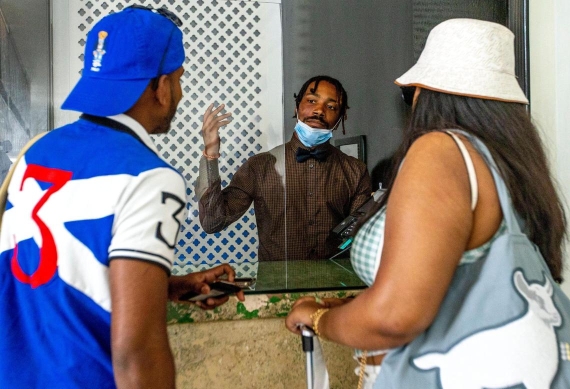 Assistant front desk manager DeAngelo Monroe, 29, center, speaks to hotel guests Sheryl Kemraj, 23, right, and Randy Gopaul, 24, as they check in at The Dream Hotel South Beach in Miami Beach, Florida, on Thursday, May 26, 2022.