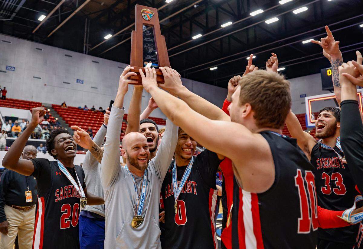 Sagemont High School basketball coach David Roe holds the State Championship Trophy as he celebrates with players after defeating Orlando Christian Prep during the FHSAA Class 2A Final at the RP Funding Center in Lakeland, Florida on Friday, March 3, 2023.