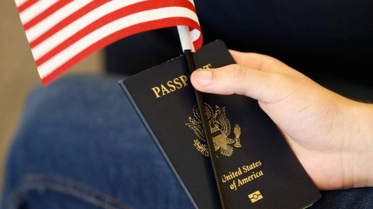 A new citizen holds an American flag and passport during a naturalization ceremony at the U.S. Citizenship and Immigration Services Kendall Office, Thursday, Aug. 30, 2018, in Miami.