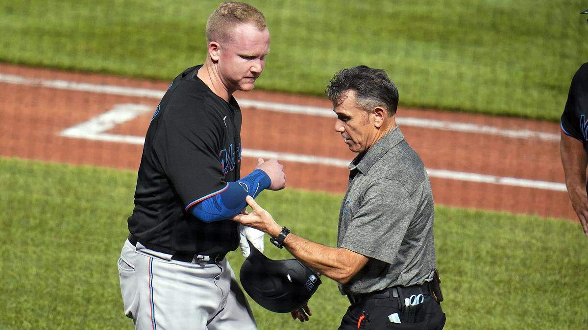 Miami Marlins’ Garrett Cooper, left, is helped by a team trainer after being hit by a pitch from Pittsburgh Pirates reliever Wil Crowe during the eighth inning of a baseball game in Pittsburgh, Saturday, July 23, 2022.