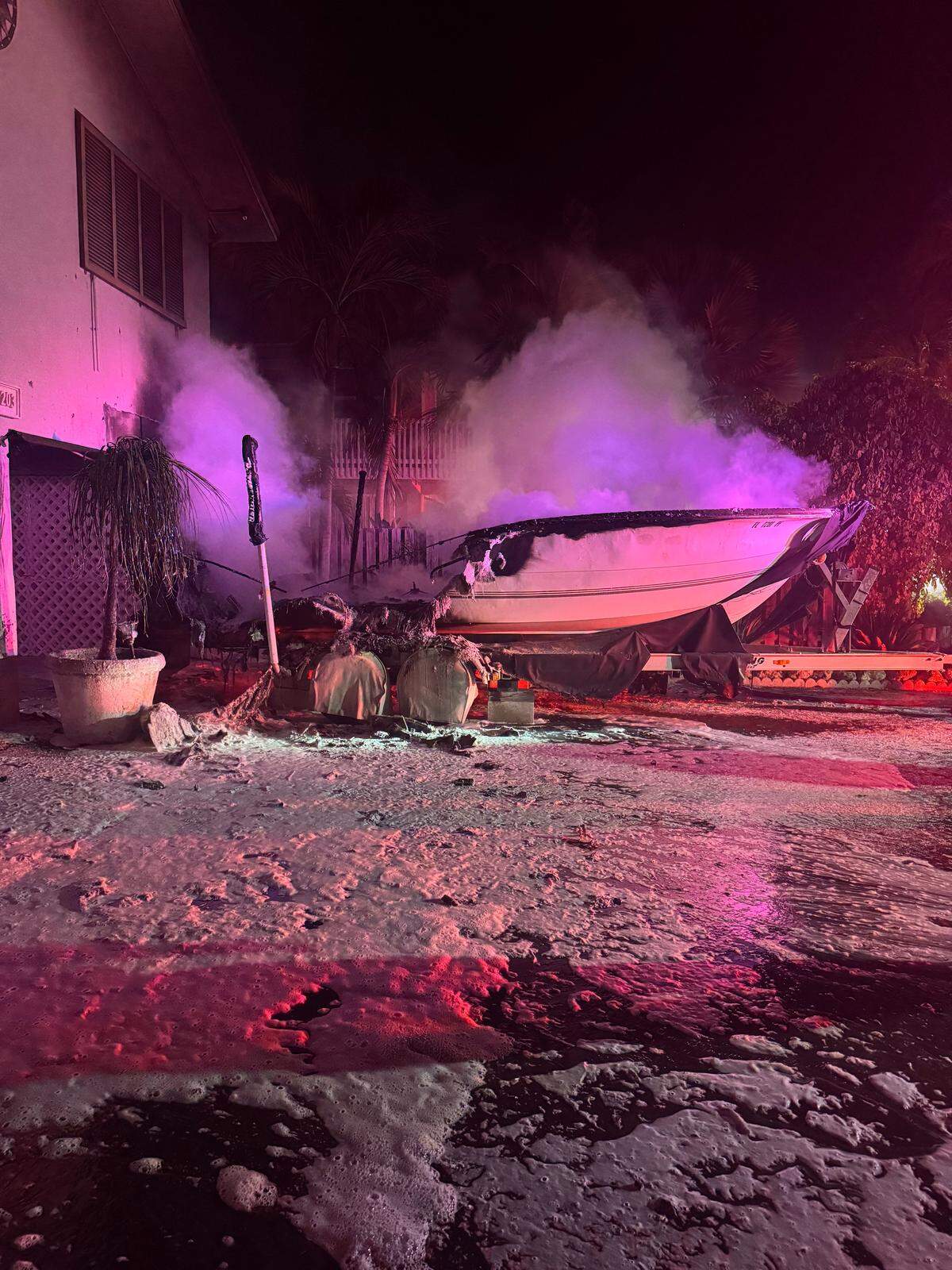 A boat parked on a trailer in front of a house in the Middle Florida Keys city of Marathon smokes from flames a Monroe Sheriff’s deputy extinguished Wednesday morning, Sept. 3, 2025.