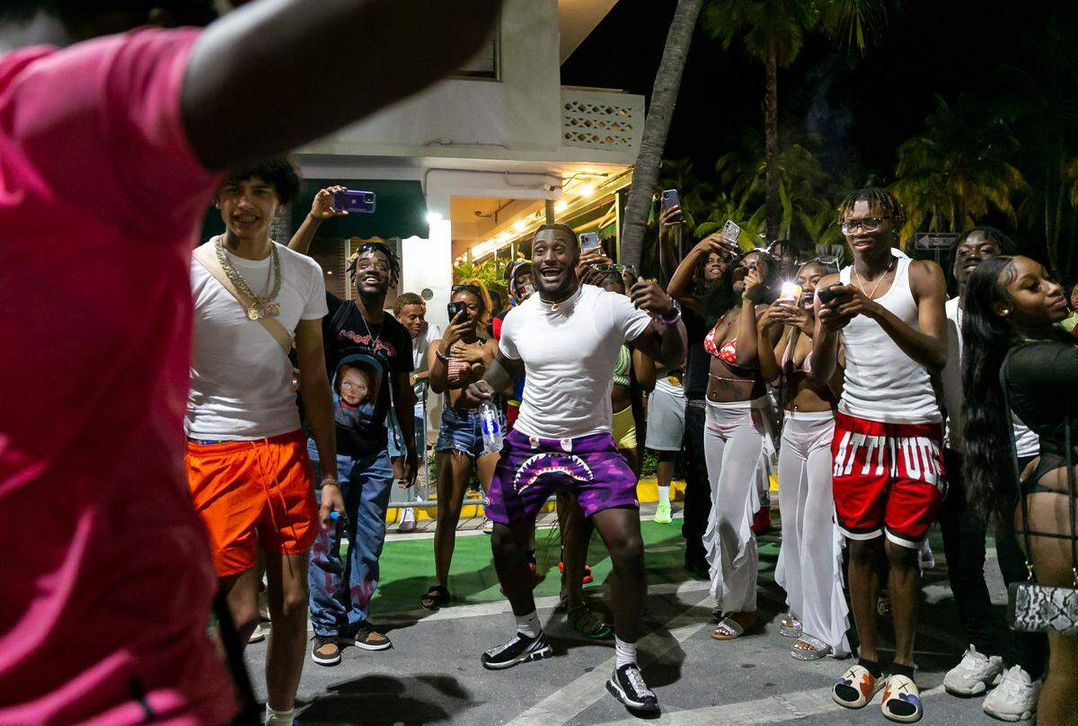 TikTokers dance and film videos on Ocean Drive and 8th Street as a crowd of people watch in Miami Beach, Florida on Friday, March 25, 2022. City officials imposed a midnight curfew and forced stores to stop selling alcohol after 6 p.m. The restrictions were set in place after two shootings in Miami Beach the weekend before caused city officials to announce a “state of emergency.”