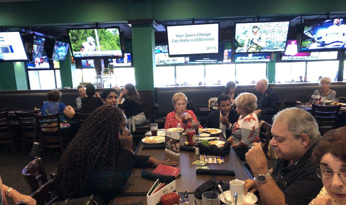 Florida Senator Daphne Campbell, D-North Miami Beach, makes a call at a Duffy’s where she and opponent Jason Pizzo (seen kneeling and speaking) answered questions from voters.