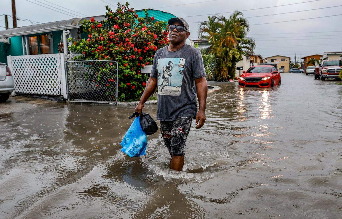 Mires Aguenar caminando por la calle inundada en Holiday Acres Mobile Home Park en Hialeah, la Florida, el miércoles 12 de junio de 2024.