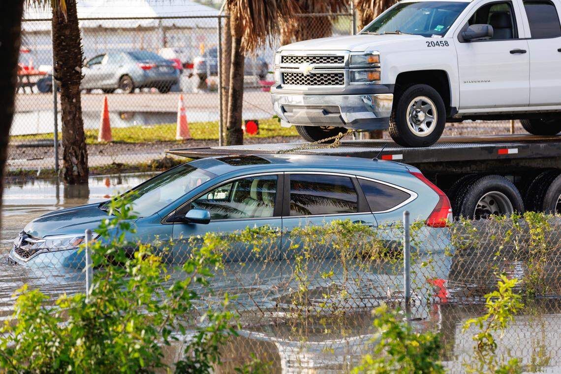 A tow truck drives through floodwater past a partly submerged vehicle on West Perimeter Road in Fort Lauderdale on Thursday, April 13, 2023.