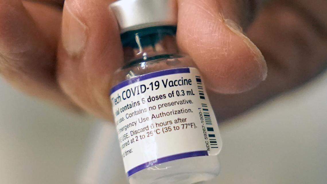 A doctor loads a dose of Pfizer COVID-19 vaccine into a syringe at a mobile vaccination clinic in Worcester, Mass.
