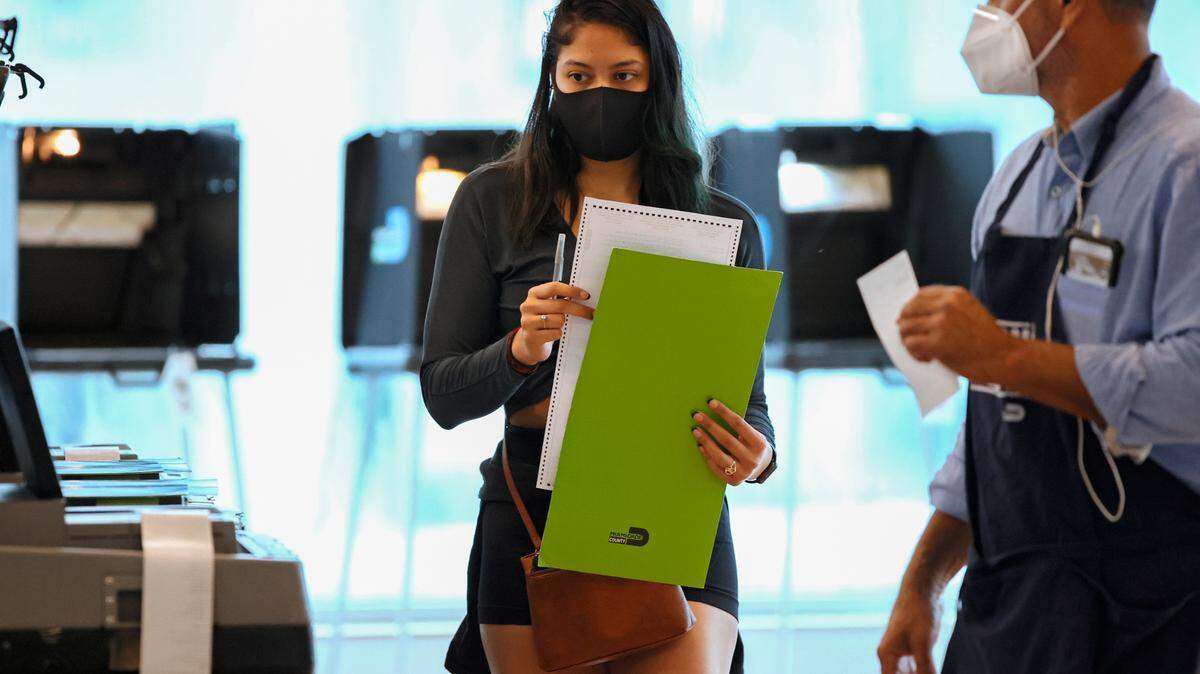 A polling worker collecting a ballot from a voter during the Miami General Municipal and Special Elections in Miami-Dade County at the Jose Marti Gym on Tuesday, Nov. 2, 2021.