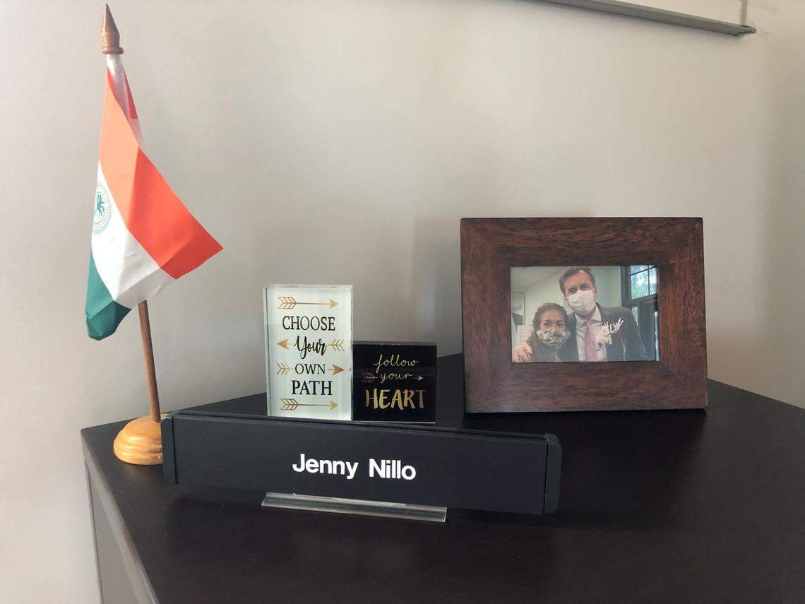 Jenny Nillo’s office at the Omni CRA building is mostly empty, including a desk with very few items on it. On the desk there’s a name plate, a few motivational quotes, a city of Miami flag, an unopened box of business cards and a framed photo of her and Alex Díaz de la Portilla.