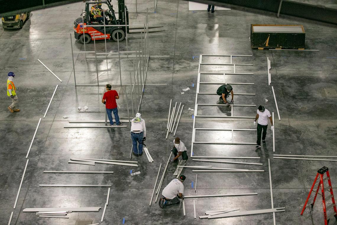 As seen from the rafters, representatives from the Army Corp of Engineers, trade contractors and employees from Robins & Morton build a coronavirus field hospital inside the Miami Beach Convention Center on Wednesday, April 8, 2020.