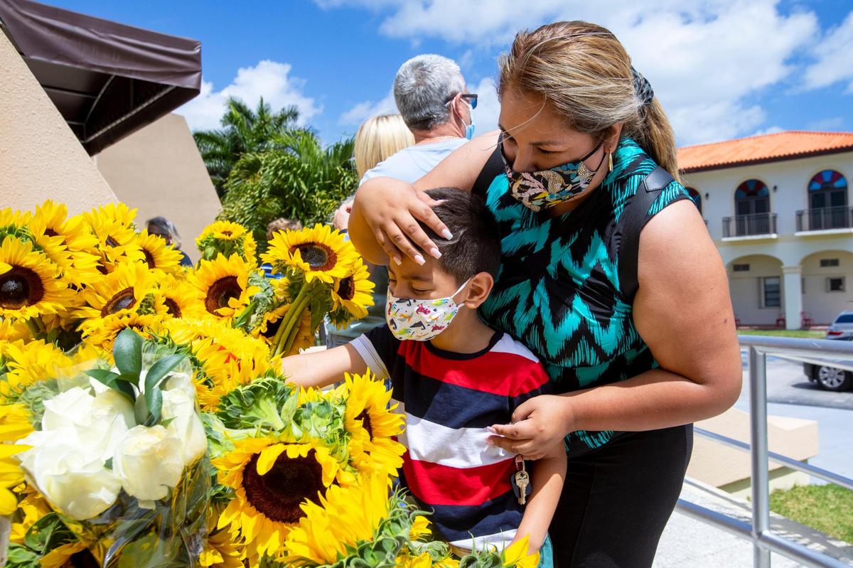 Janet Hidalgo, de 34 años, y su hijo, Gustavo Galindo, de 5, dejan un ramo de girasoles durante una oración por la reunificación de las familias cubanas en la Ermita de la Caridad en Miami, Florida, el domingo 14 de marzo de 2021.