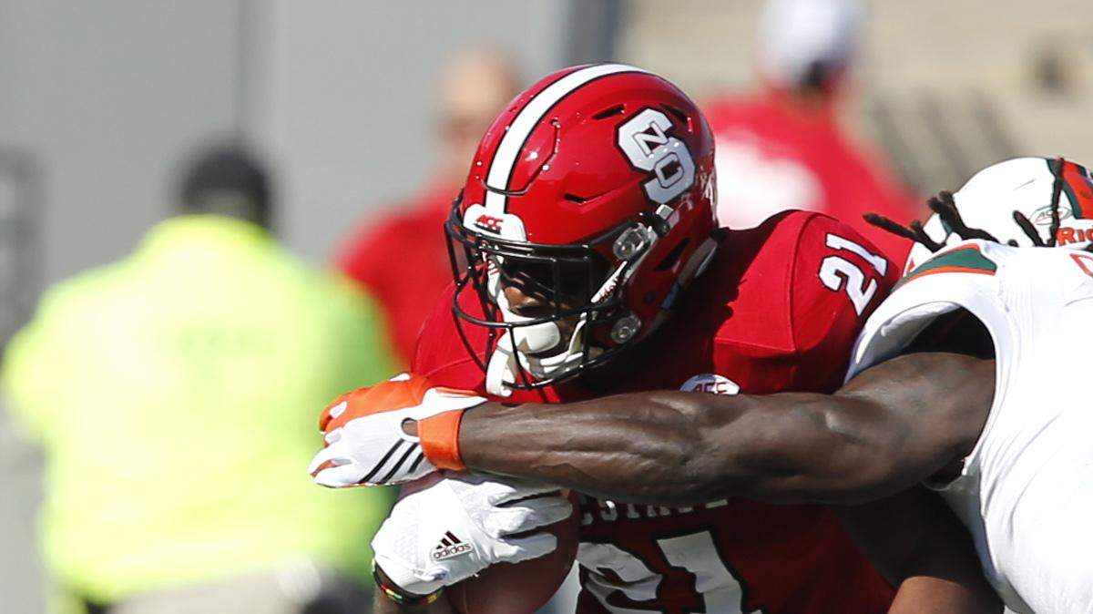 North Carolina State running back Matt Dayes (21) is tackled by Miami's Shaquille Quarterman (55) and Jamal Carter Sr. (6) during the first half of an NCAA college football game at Carter-Finley Stadium in Raleigh, N.C., Saturday, Nov. 19, 2016.