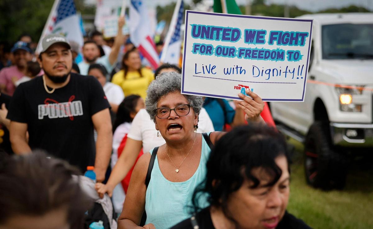 Leticia Puente carries a “United We Fight for Our Freedom to Live with Dignity!” poster as she joins protesters marching along US1 in Homestead, Florida during a “Freedom For All” rally against the bills passed by the Florida Legislature and signed into law by Gov. Ron DeSantis on Saturday, July 1, 2023.