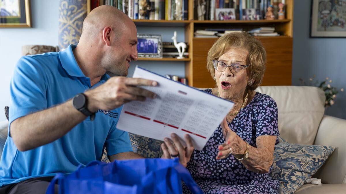 Zach Goodstat, care manager of the Holocaust Survivor Assistance Program with the Goodman Jewish Family Services, hands Ruth Di Stefano, a 97-year-old Holocaust survivor, a calendar at her home on Friday, Sept. 19, 2025, in Fort Lauderdale, Fla. Di Stefano received a free gift bag from Goodman Jewish Family Services containing a calendar, apples, candles, honey, and grape juice in anticipation of the Rosh Hashana holiday.