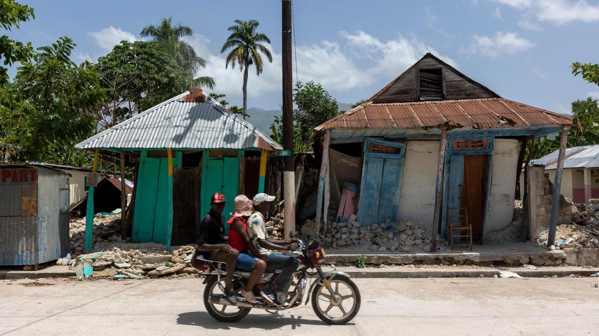 Men ride by quake-damaged homes in Maniche, Haiti, on Aug. 23, 2021.