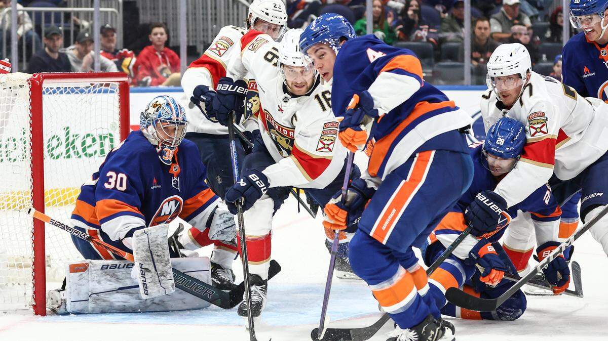 Mar 16, 2025; Elmont, New York, USA; Florida Panthers center Aleksander Barkov (16) and New York Islanders defenseman Tony DeAngelo (4) chase after the puck in the third period at UBS Arena.
