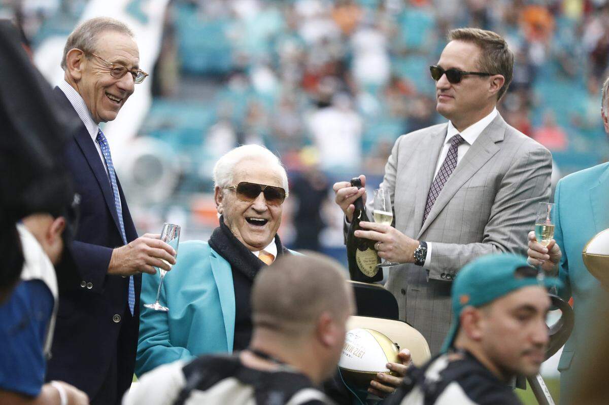 Miami Dolphins owner Stephen Ross, left, toasts, former head coach Don Shula, during a halftime celebration of the 1972 undefeated team during Dec. 22, 2019 game against the Cincinnati Bengals. He’s teaming up with former players to distribute meals during the coronavirus crisis.
