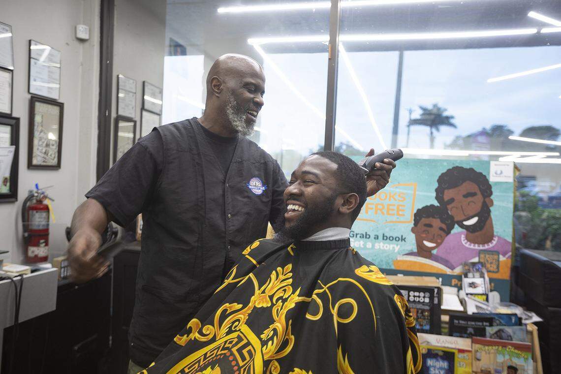 (L) Barber Michael Amaya chats with (R) Jefferson Noel, Founder of Barbershop Speaks, as he cuts Noel’s hair at Topcuttaz barbershop in Miami Gardens.