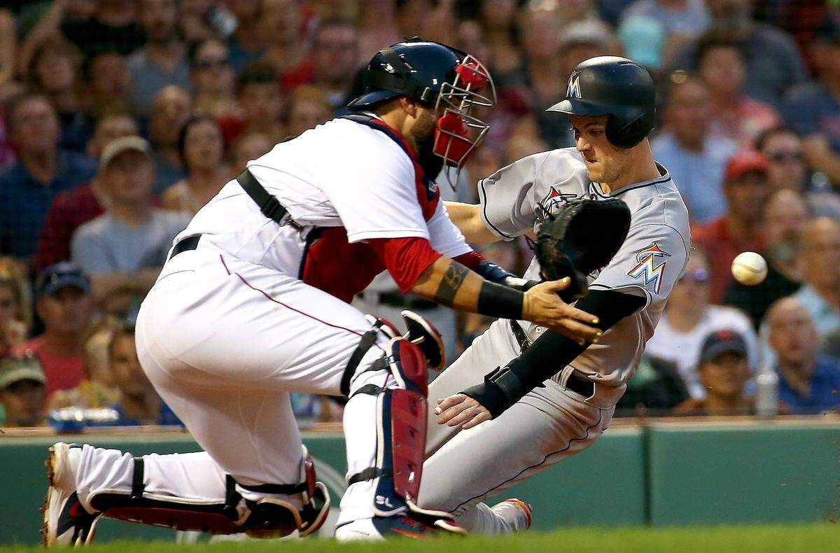 Brian Anderson #15 of the Miami Marlins scores as Sandy Leon #3 of the Boston Red Sox fields a late throw in the third inning at Fenway Park on August 29, 2018 in Boston, Massachusetts.