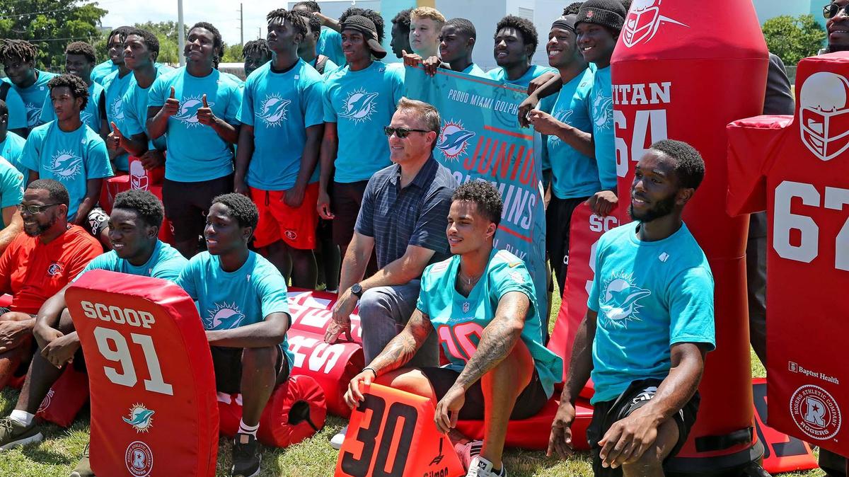 Miami Dolphins receiver Kenny Stills and Miami Dolphins CEO Tom Garfinkel pose with donated football equipment along with the Miami Edison football team, July 23, 2019. The Miami Dolphins and Baptist Health South Florida donated football equipment to Miami Edison Senior High School after the team’s field house burned in June, damaging much of their equipment.
