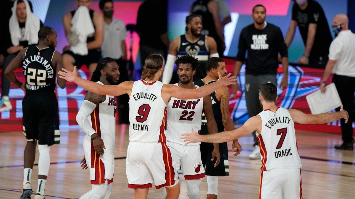 Kelly Olynyk (9) y Jimmy Butler (22) del Heat reaccionan con sus compañeros de equipo después de que el Heat venciera a los Milwaukee Bucks 116-114 en un partido de semifinales de la conferencia de la NBA el miércoles 2 de septiembre de 2020 en Lake Buena Vista.