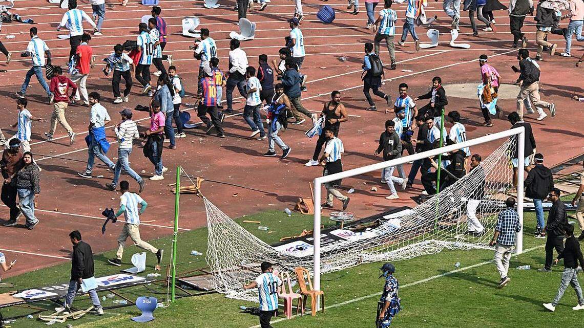 Security personnel try to control the crowd as Argentina's footballer Lionel Messi departs from Salt Lake Stadium during his GOAT Tour in Kolkata on December 13, 2025. Angry spectators broke down barricades and stormed the pitch at a stadium in India after football star Lionel Messi, who is on a three-day tour of the country, abruptly left the arena. As a part of a so-called GOAT Tour, the 38-year-old Argentina and Inter Miami superstar touched down in the eastern state of West Bengal early on December 13, greeted by a chorus of exuberant fans chanting his name. (Photo by Dibyangshu SARKAR / AFP via Getty Images)