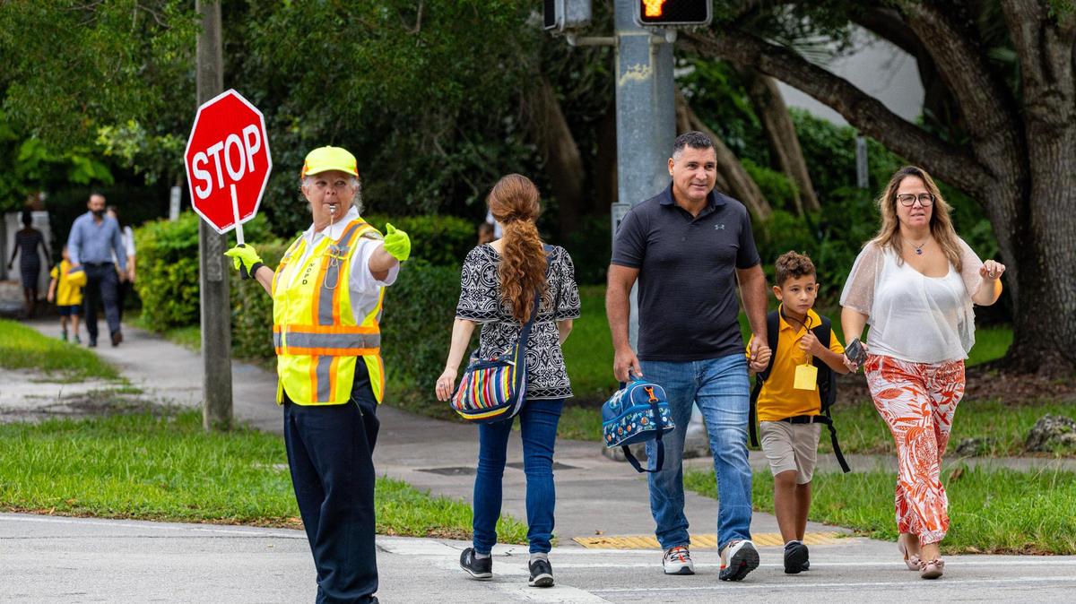 MDPD crossing guard Josefina Vina guides parents and children on the first day of school at Sunset Elementary in Miami, Florida, on Thursday, Aug. 17, 2023.
