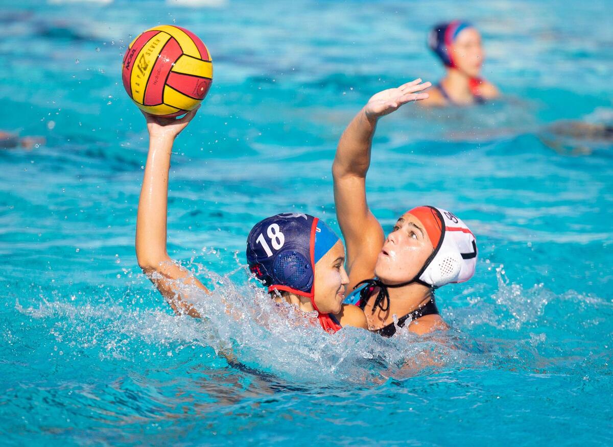 A MAST player (18) rises out of the water to keep the ball from Miami Beach’s Asia Zrihen (7) during the second quarter of the GMAC girls water polo finals on Wednesday, March 20, 2024, at MAST Academy on Virginia Key.