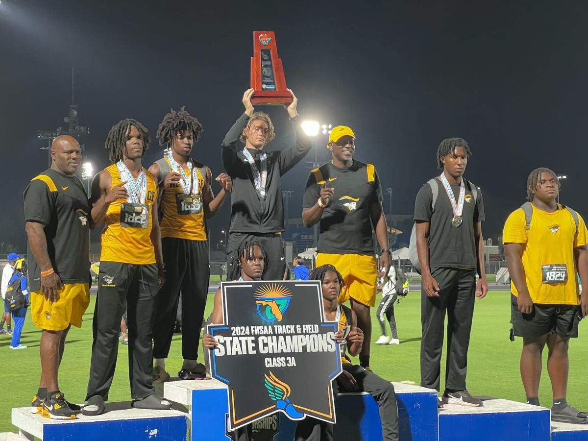 The American Heritage boys’ track and field team poses with the Class 3A state championship trophy on Friday at Hodges Stadium in Jacksonville, Fla.