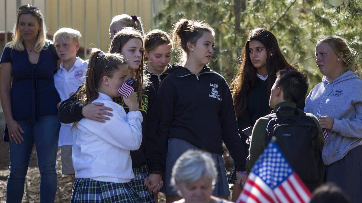 Young people talk after the procession carrying the body of Ventura County Sheriff Sgt. Ron Helus, who was killed in a mass shooting at the Borderline Bar and Grill, left Los Robles Hospital on Thursday in Thousand Oaks, California. A dozen people have died including the sergeant plus the gunman.
