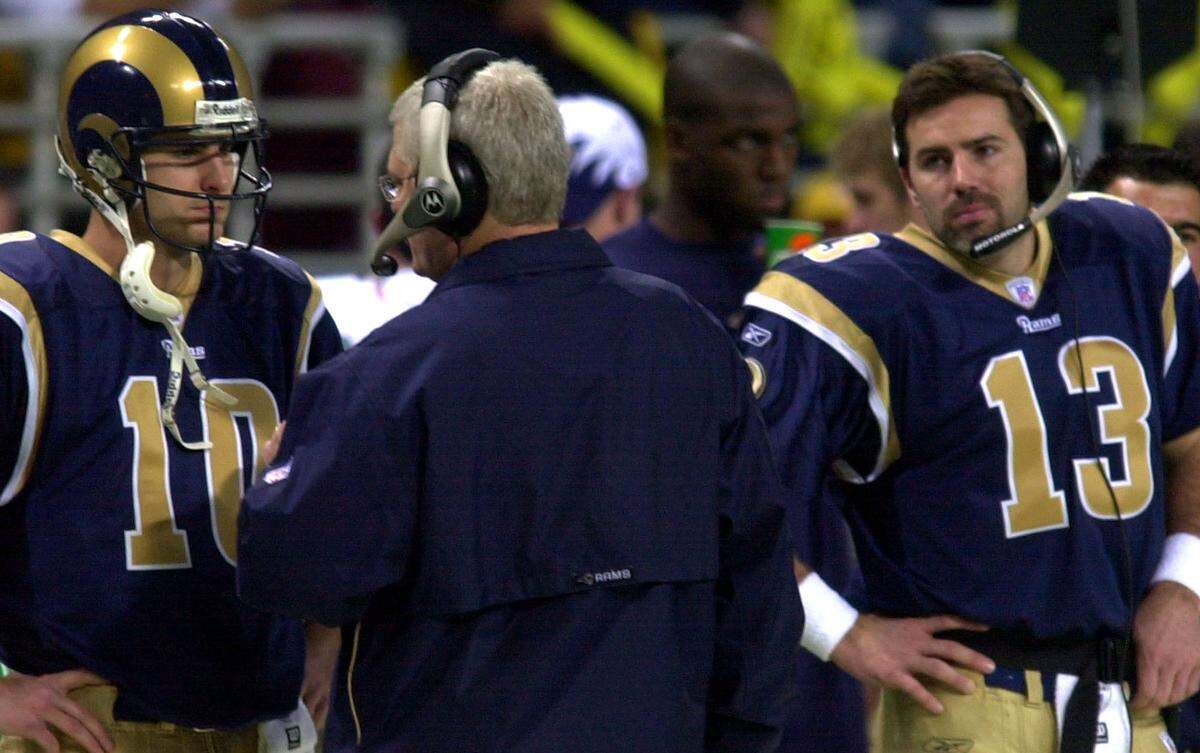 St Louis Rams coach Mike Martz, center, talks with quarterback Marc Bulger, left, as backup quarterback Kurt Warner looks on during the fourth quarter of their NFC playoff game against the Carolina Panthers in St. Louis, Saturday, Jan. 10, 2004.