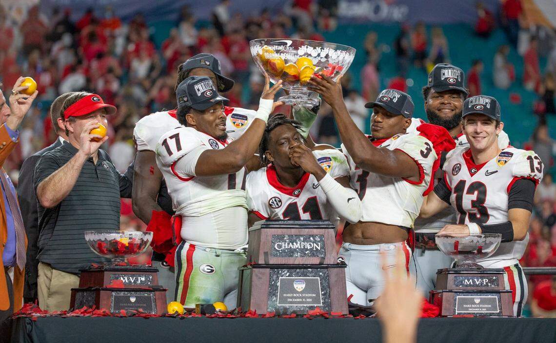 Georgia Bulldogs defensive back Derion Kendrick (11) bites into an orange as teammates celebrate with the championship trophy after defeating Michigan Wolverines during the 2021 College Football Playoff Semifinal at the Capital One Orange Bowl hosted at Hard Rock Stadium in Miami Gardens, Florida, on Friday, December 31, 2021.