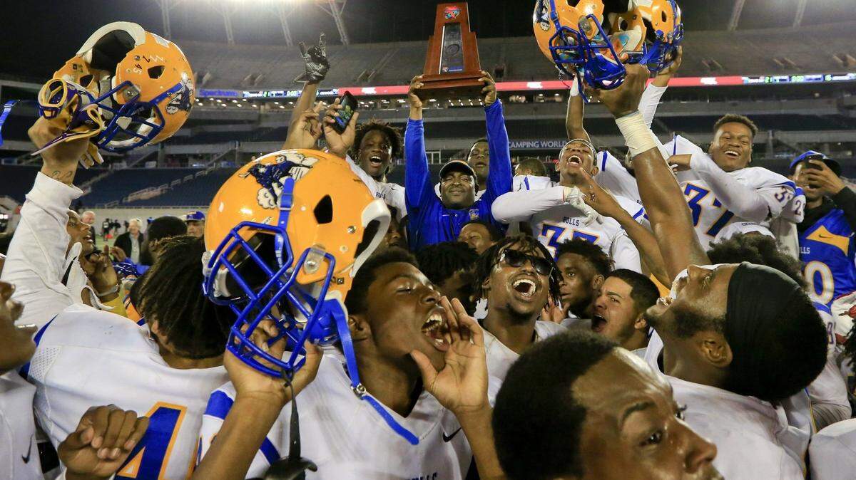 Miami Northwestern Bulls head coach Max Edwards holds the championship trophy as the team celebrates after defeating Armwood Hawks 21-16 in the Class 6A state high school football championship in Orlando on Friday, Dec. 8, 2017. DaMarco Keshaun Harris, who was on that team, was shot to death Thursday, May 9, 2024, in a Midtown Miami parking lot.