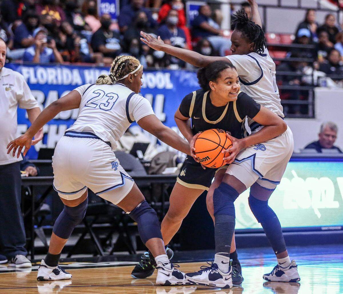 Miami Highs Joelle Wilson (22) looks to pass as Dr. Phillips High Schools Ronnice Berry (23) and Kalea’ Rainey (1) defend in the Class 7A girls basketball state championship at the RP Funding Center in Lakeland on Saturday, February 26, 2022.
