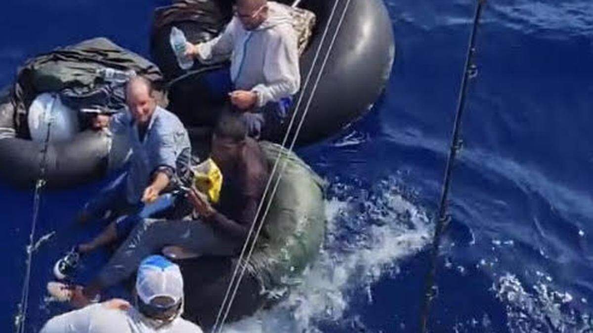 Mike Diaz, a mate on the Takedown Charters fishing boat out of Islamorada, passes a lit cigarette to four men who migrated by inner tube from Cuba. Diaz and his boss, Capt. Greg Hartlaub, encountered the men at sea on Friday, May 6, 2022.