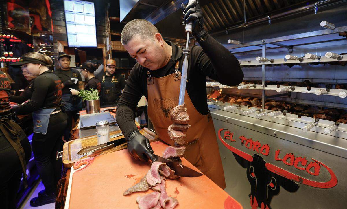 Grill Master Ramon Rodriguez cuts meat in the kitchen at El Toro Loco Steakhouse restaurant in Little Havana. 