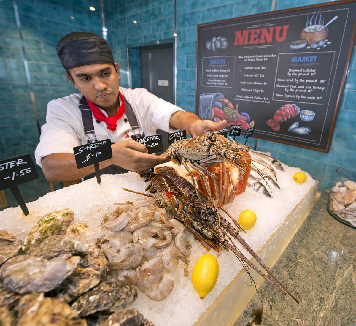 A chef positions a spiny lobster in a display case at Carnival Horizon’s Seafood Shack.