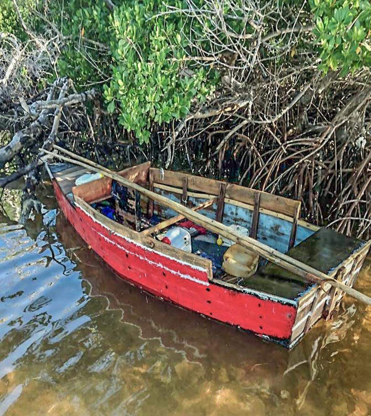A red, wooden boat floats in the mangroves on the shores of the Middle Florida Keys city of Marathon Tuesday, Sept. 28, 2021. The U.S. Border Patrol says 10 men from Cuba were on the vessel.