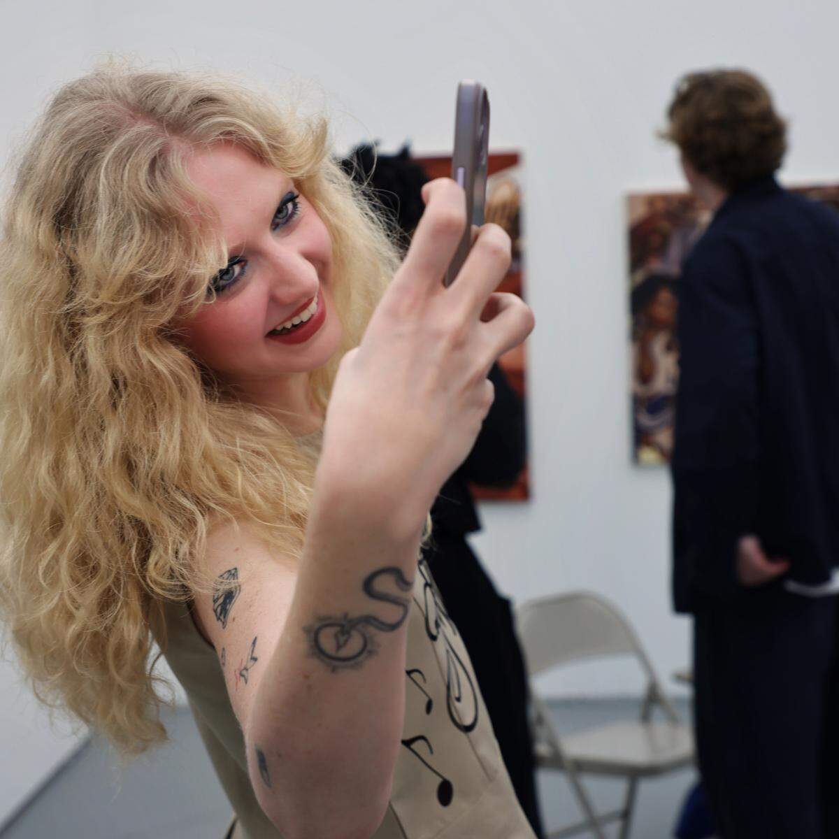 Miami Beach, FL, December 2, 2025 -  Carina Allen takes a photo of her artist girlfriend as she stood by her art at Untitled Art fair