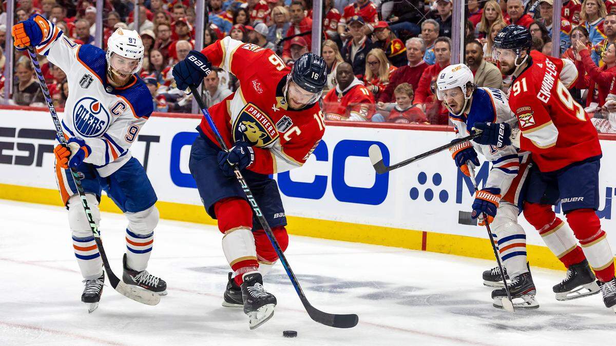 Sunrise, Florida, June 8, 2024 - Florida Panthers center Aleksander Barkov (16) second from left attempts to control the puck as Edmonton Oilers center Connor McDavid (97), left defends him during second period action in game 1 of the Stanley Cup Final at Amerant Arena in Sunrise, Florida.