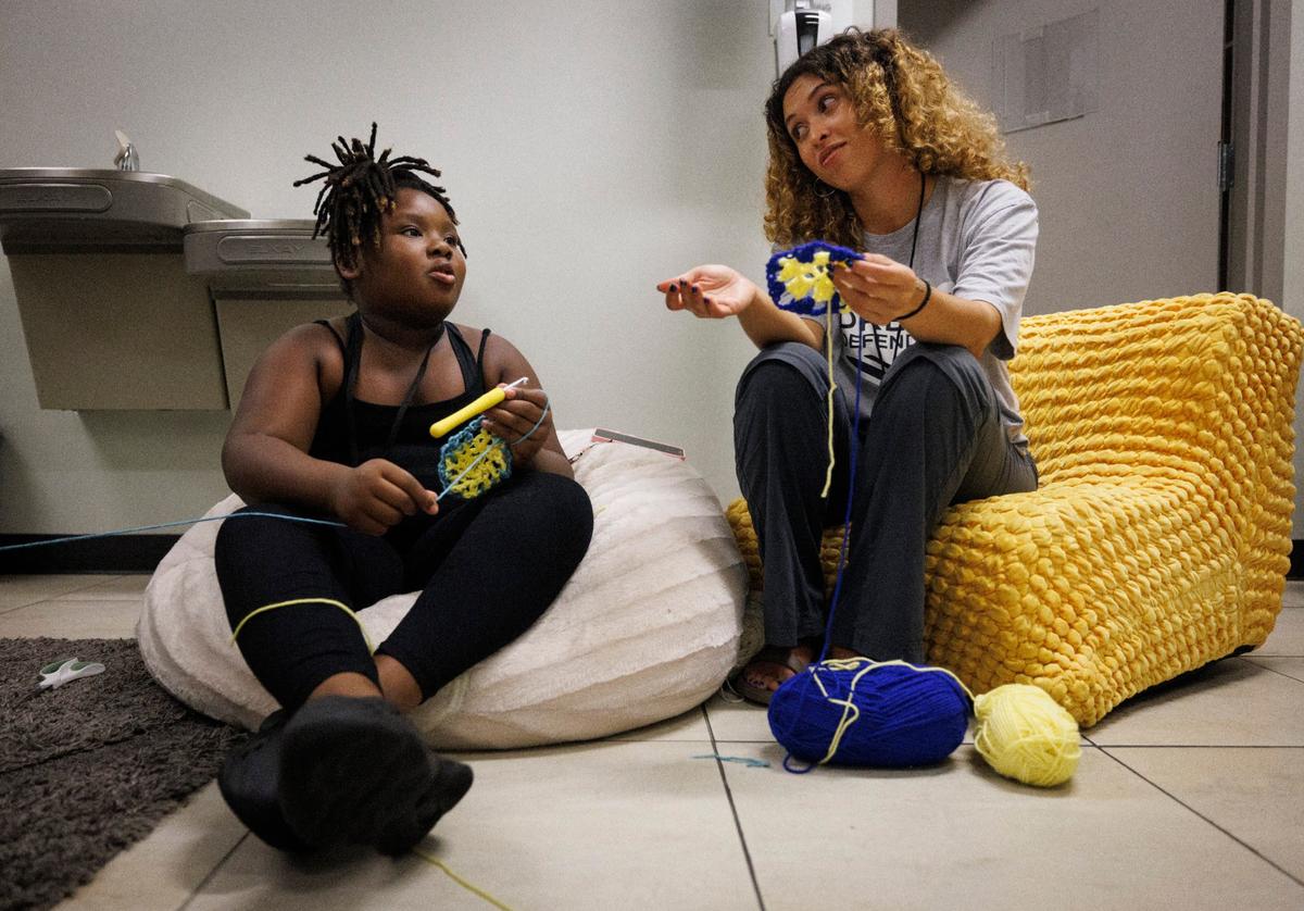 Sariyah Everett, 8, left, does crochet with Pam Zapata, clinical therapist, in the Quiet Room during the Dream Defenders’ Peace Summit camp for kids and teenagers on Thursday, June 20, 2024 at Sandrell Rivers Theater in Miami. Everett taught herself to crochet on Youtube.