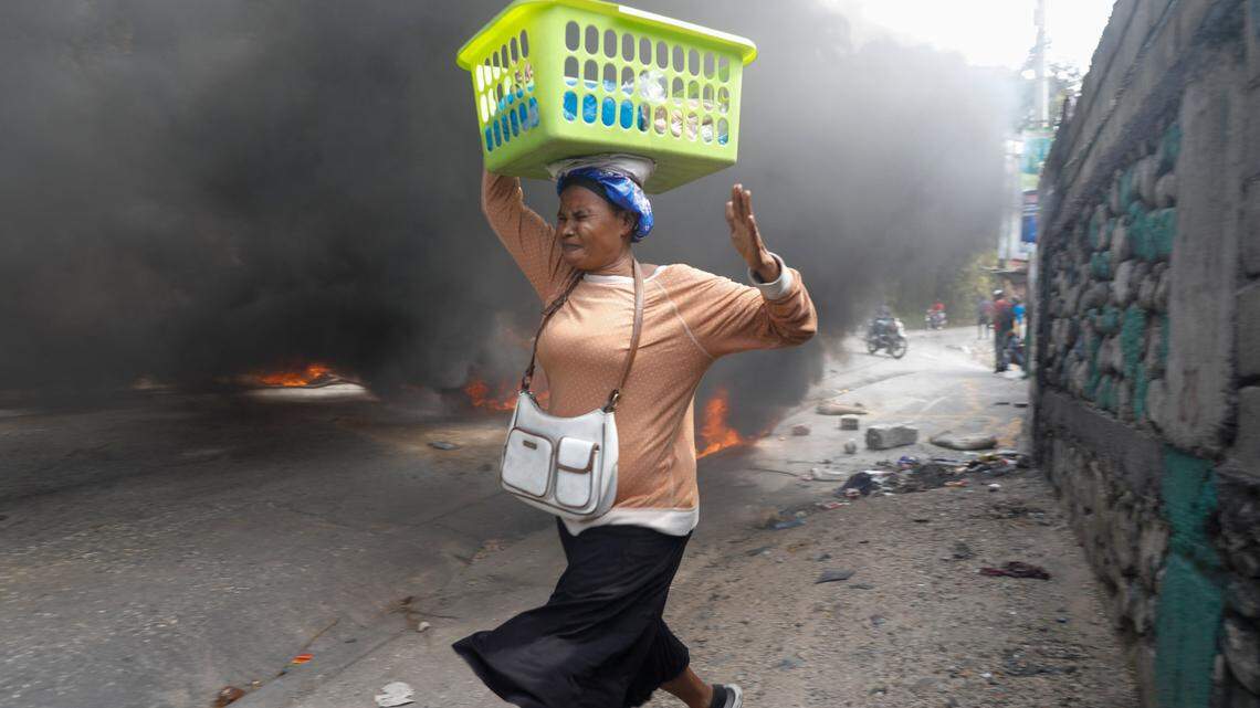 A woman runs past burning tires set by protesters against Haitian Prime Minister Ariel Henry in Port-au-Prince, Haiti, Monday, Feb. 5, 2024. (AP Photo/Odelyn Joseph)