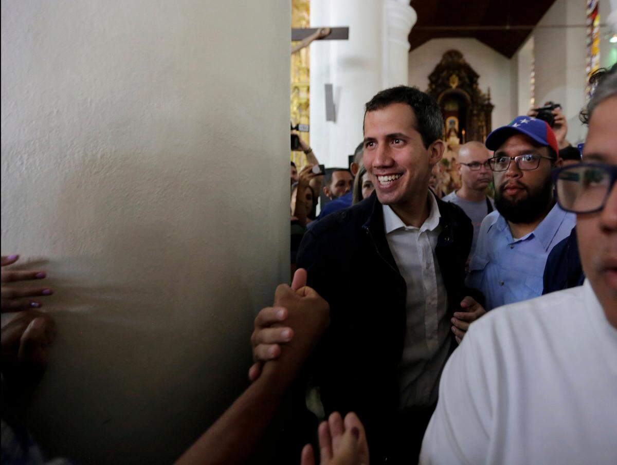 Opposition National Assembly leader Juan Guaido, right, who declared himself interim president, greets supporters as he leaves church after Mass in Caracas, Venezuela, Sunday, Jan. 27, 2019. Guaido says he is acting in accordance with two articles of the constitution that give the National Assembly president the right to hold power temporarily and call new elections.