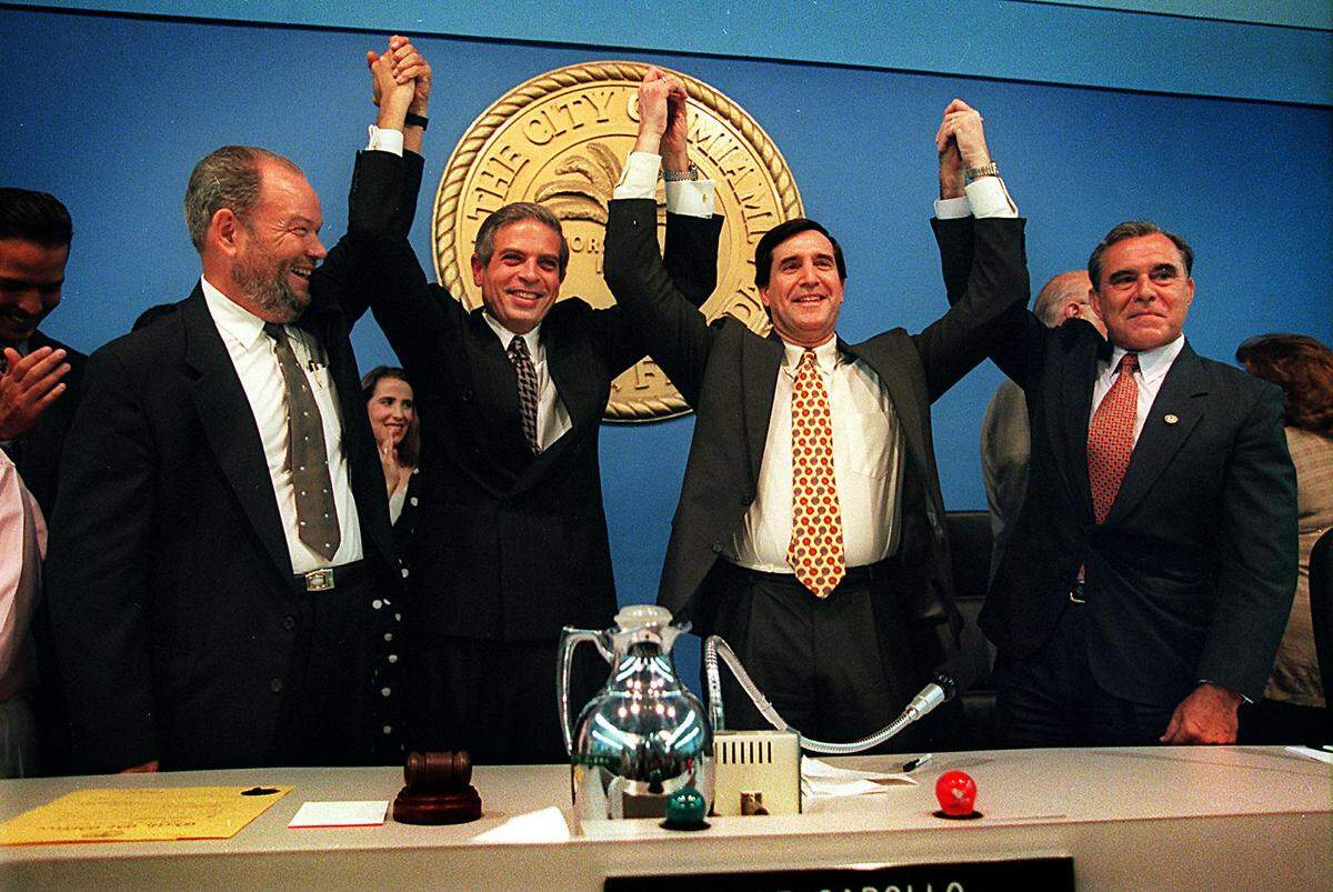 City of Miami Commissioner J.L. Plummer, left, clasps hands with new Commissioner Tomas Regalado, who is joined by Mayor Joe Carollo and Vice Mayor Willy Gort after Regalado’s swearing-in ceremony in September 1996.