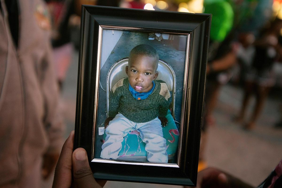 A photo of Noah Sneed is held during a gathering to honor his life with a candlelight memorial in front of Ceressa’s Daycare & Preschool, Tuesday, July 30, 2019.