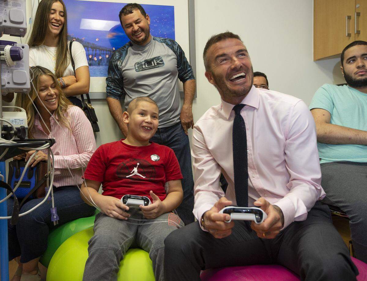 David Beckham plays a soccer video game with patient Luis Rayo, 9, as he visits children being treated for cancer at Nicklaus Children’s Hospital on Wednesday, July 11, 2018.