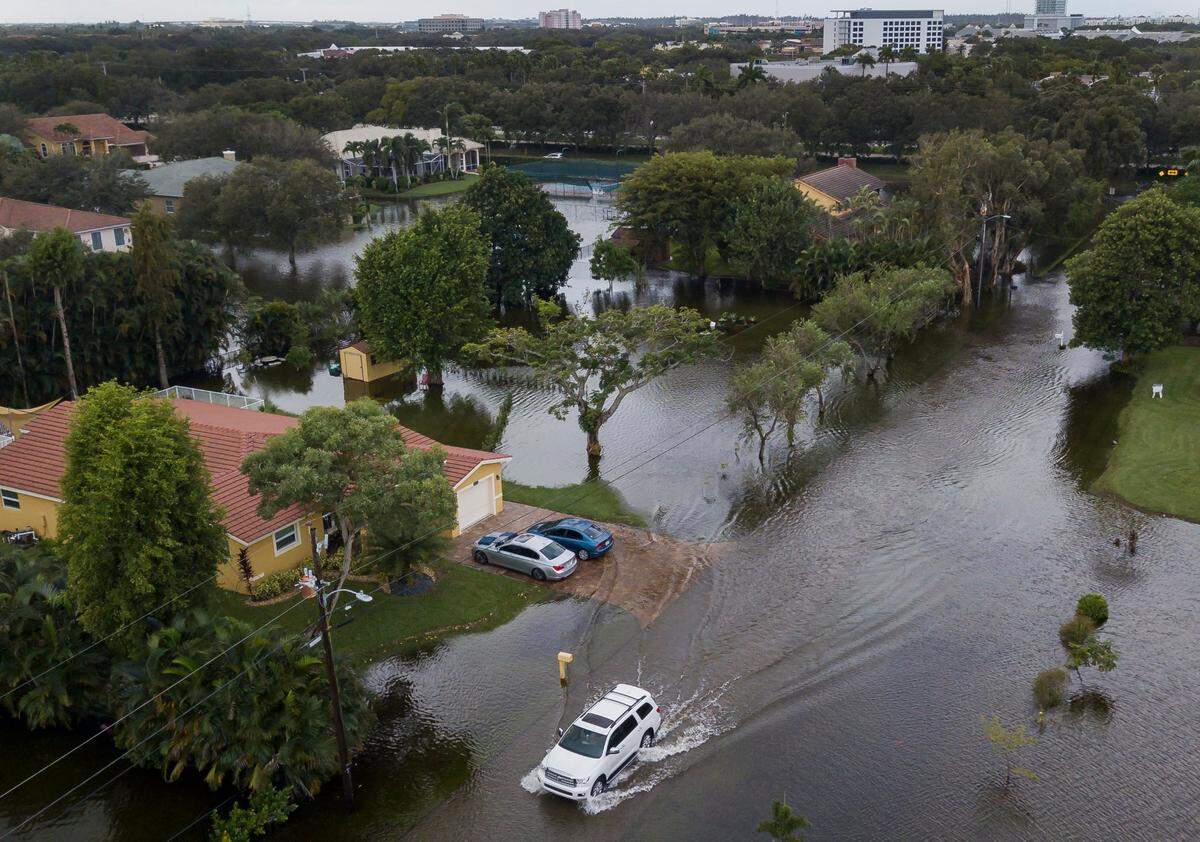 A car drives through a flooded street in a residential neighborhood in Plantation, Florida, on Monday, Nov. 9, 2020. Tropical Storm Eta made its way past South Florida Sunday night, leaving roads and neighborhoods flooded.