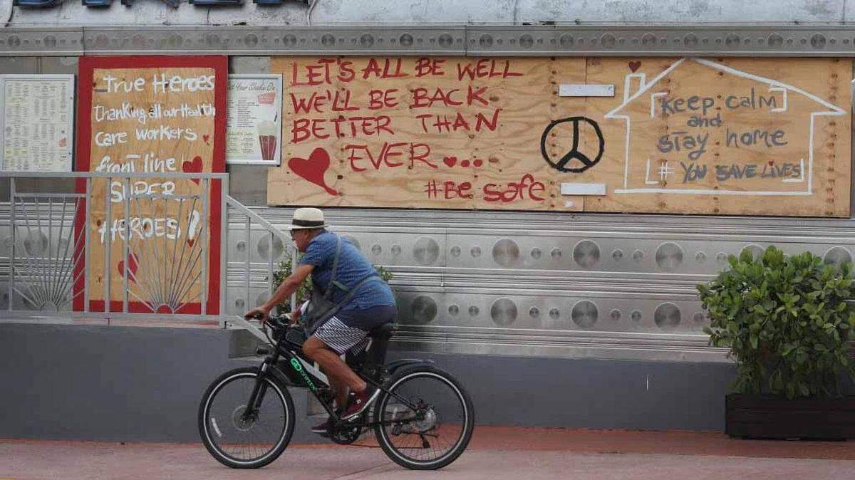Man bicycles past a sign in Miami-Dade with an optimistic message that sees past the coronavirus pandemic.
