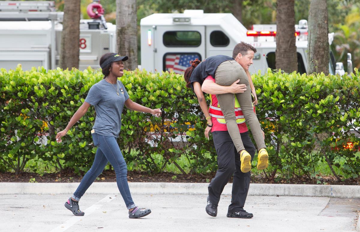 A man carries a girl after an explosion injured multiple people at the Fountains shops in Plantation on Saturday, July 6, 2019.