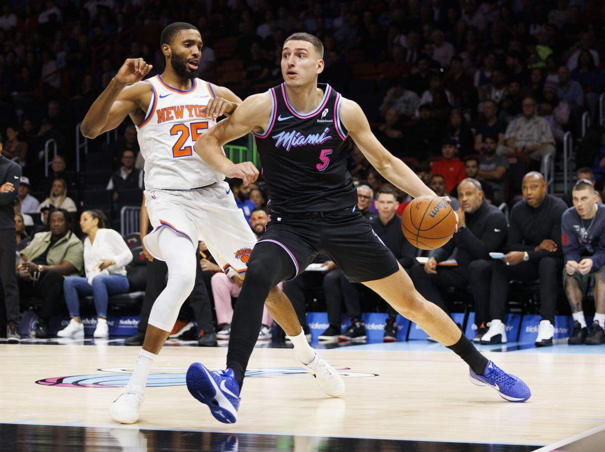 Miami Heat forward Nikola Jovic (5) dribbles around New York Knicks guard Mikal Bridges (25) during the first half of a game on Nov. 17, 2025, at Kaseya Center in Miami.