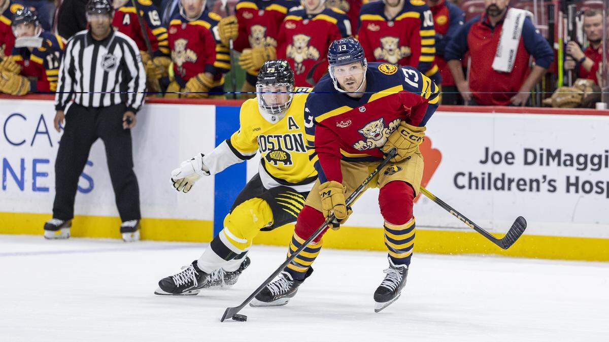 Florida Panthers center Sam Reinhart (13) looks to pass the puck as Boston Bruins defenseman Charlie McAvoy (73) defends in an overtime period of their NHL game at the Amerant Bank Arena on Wednesday, Feb. 4, 2026, in Sunrise, Fla.